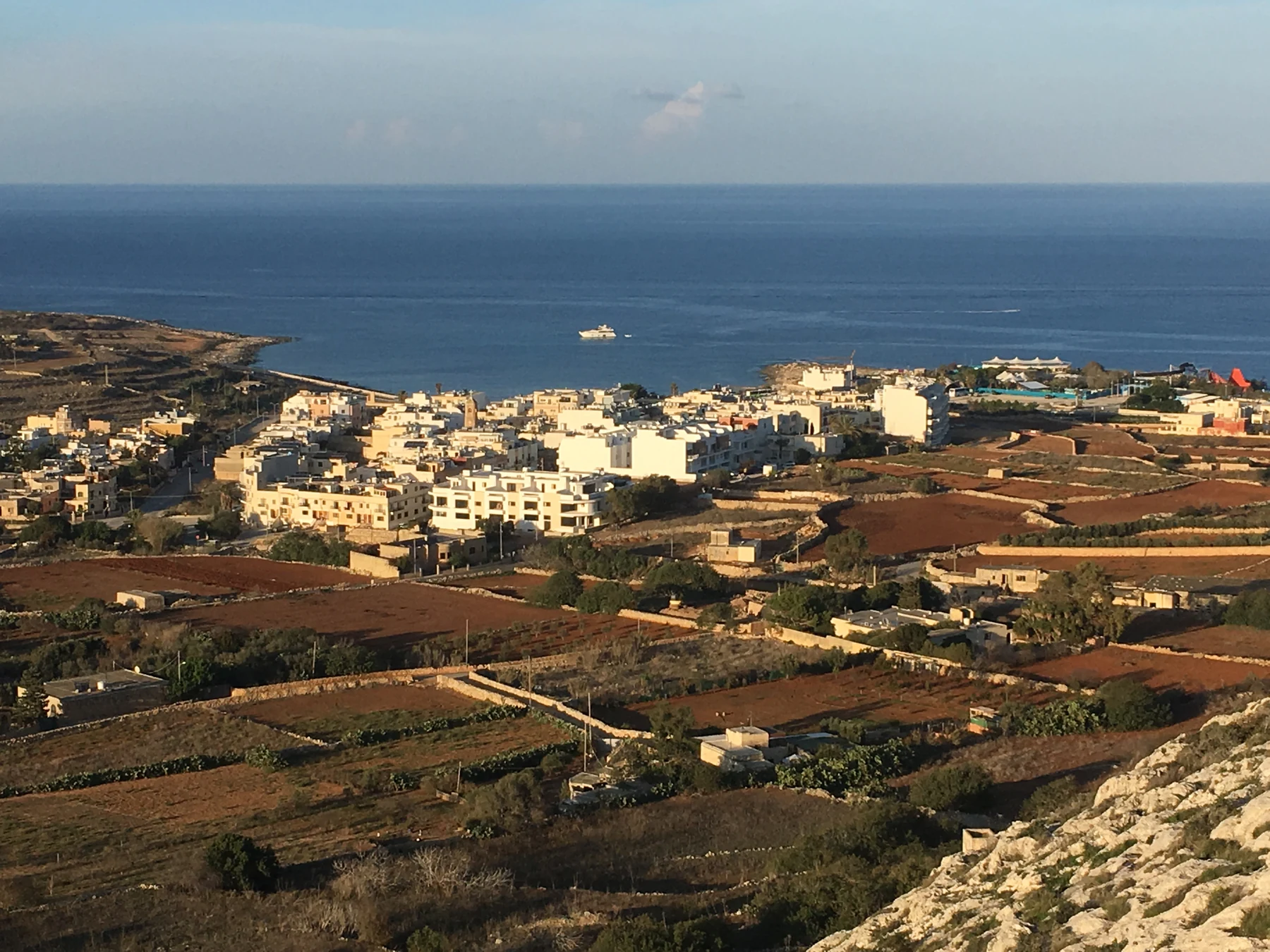 Broad view across fields and Baħar iċ-Ċagħaq towards the sea
