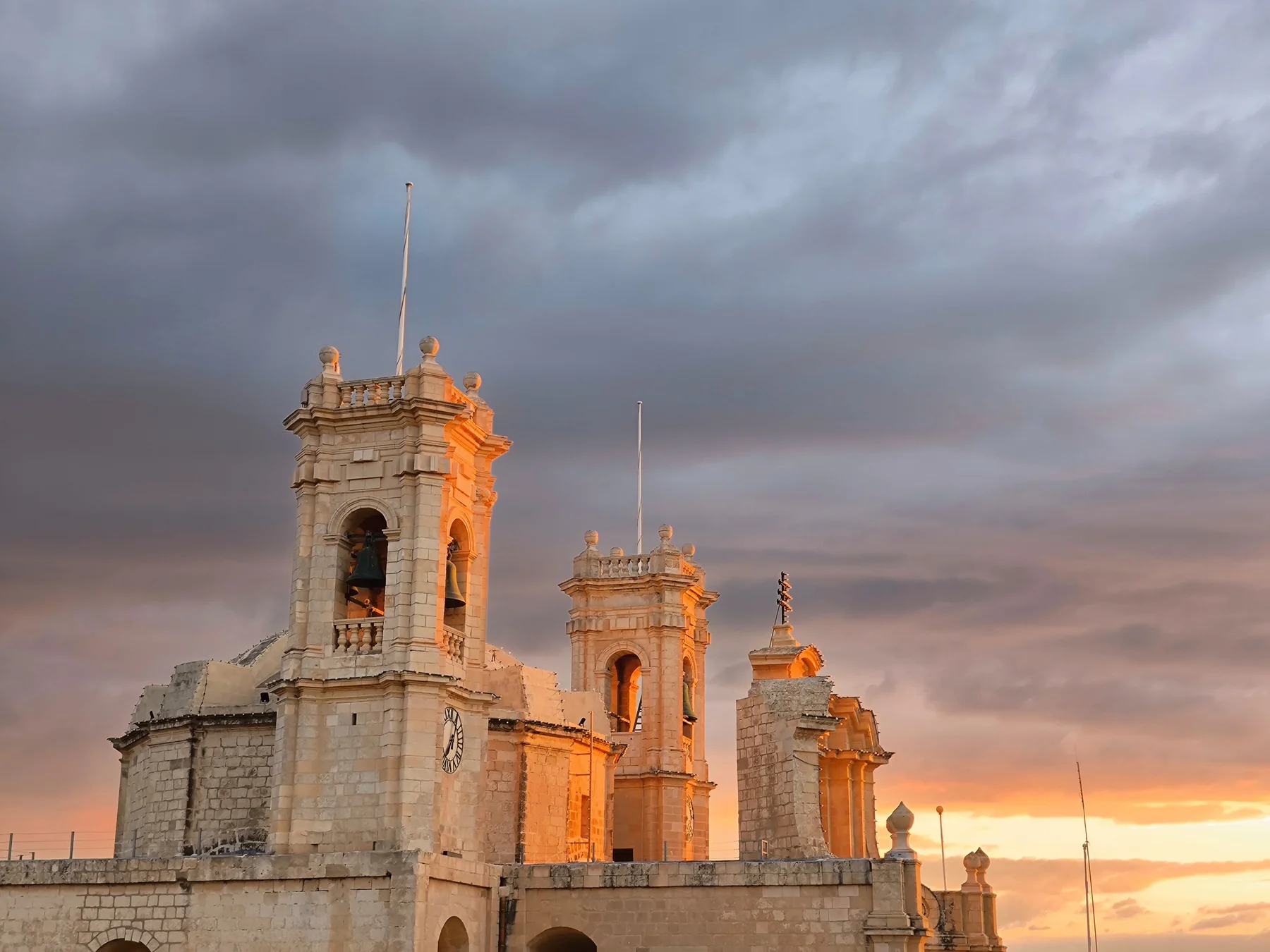 Parish church and village roofs in L-Għarb, Gozo, under a warm evening sky