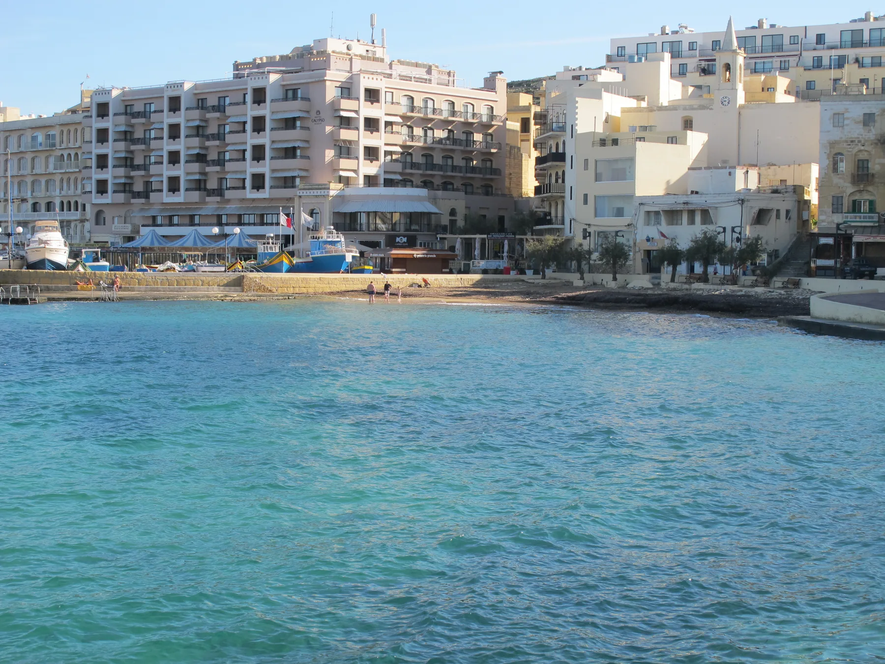 Marsalforn Bay, small beach, boats and waterfront buildings on Gozo