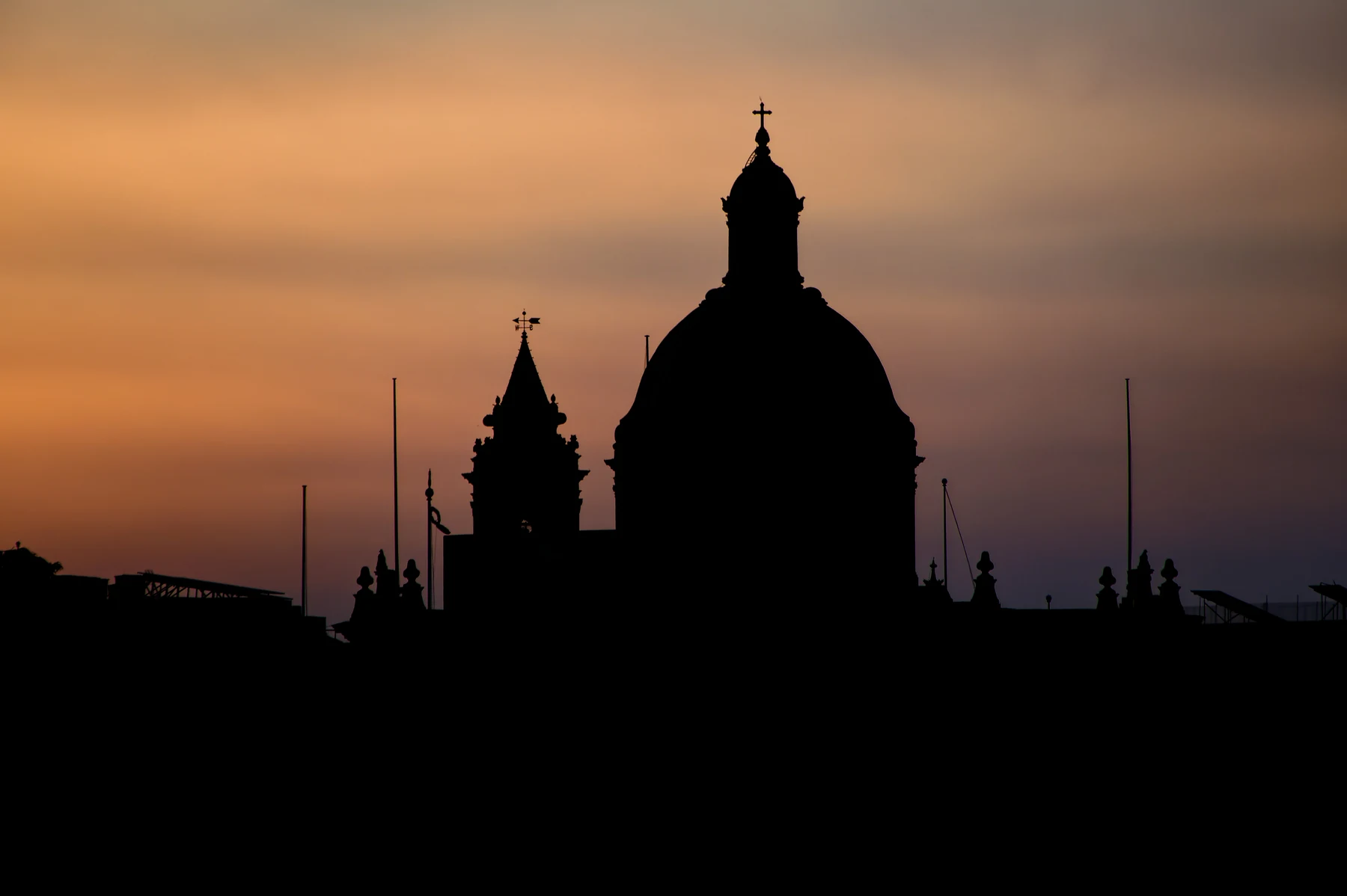 Silhouette of the Żabbar parish church against an orange evening sky