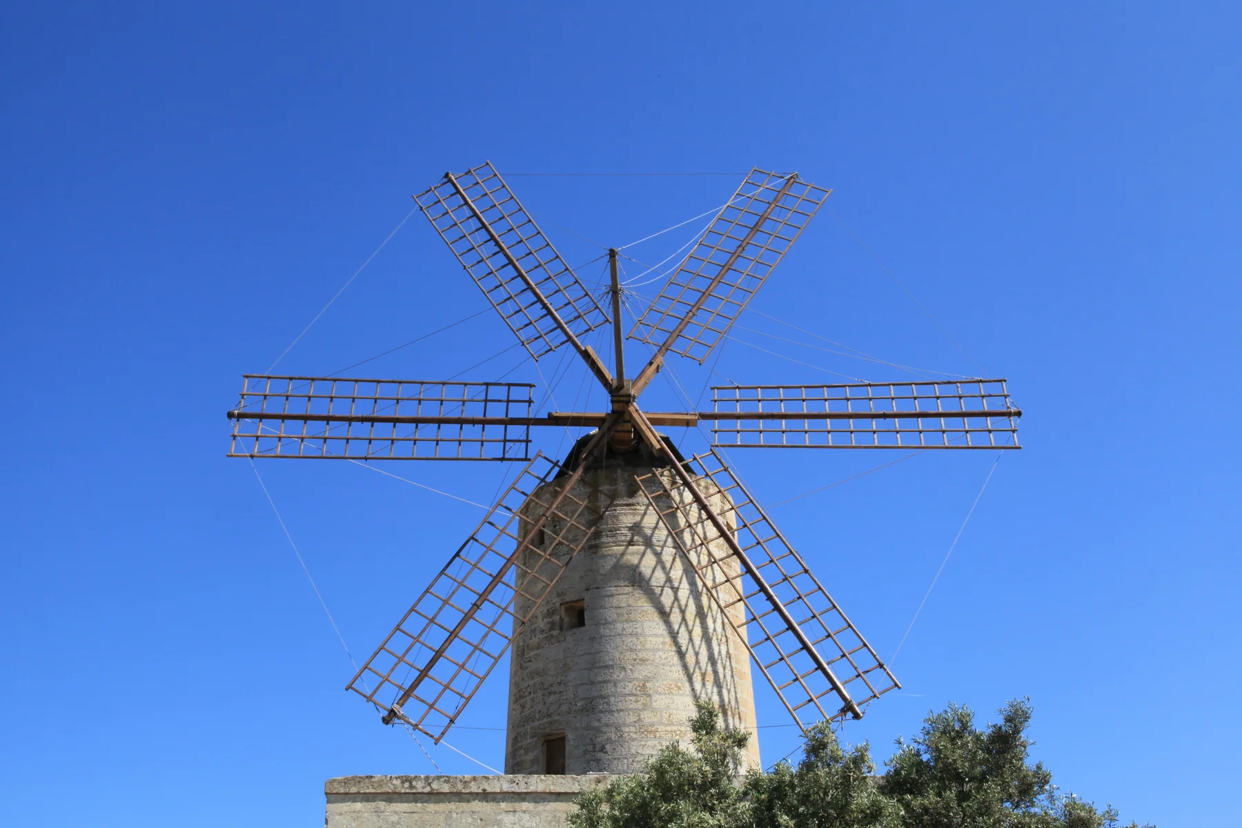 Xarolla windmill in Żurrieq with its sails against a blue sky